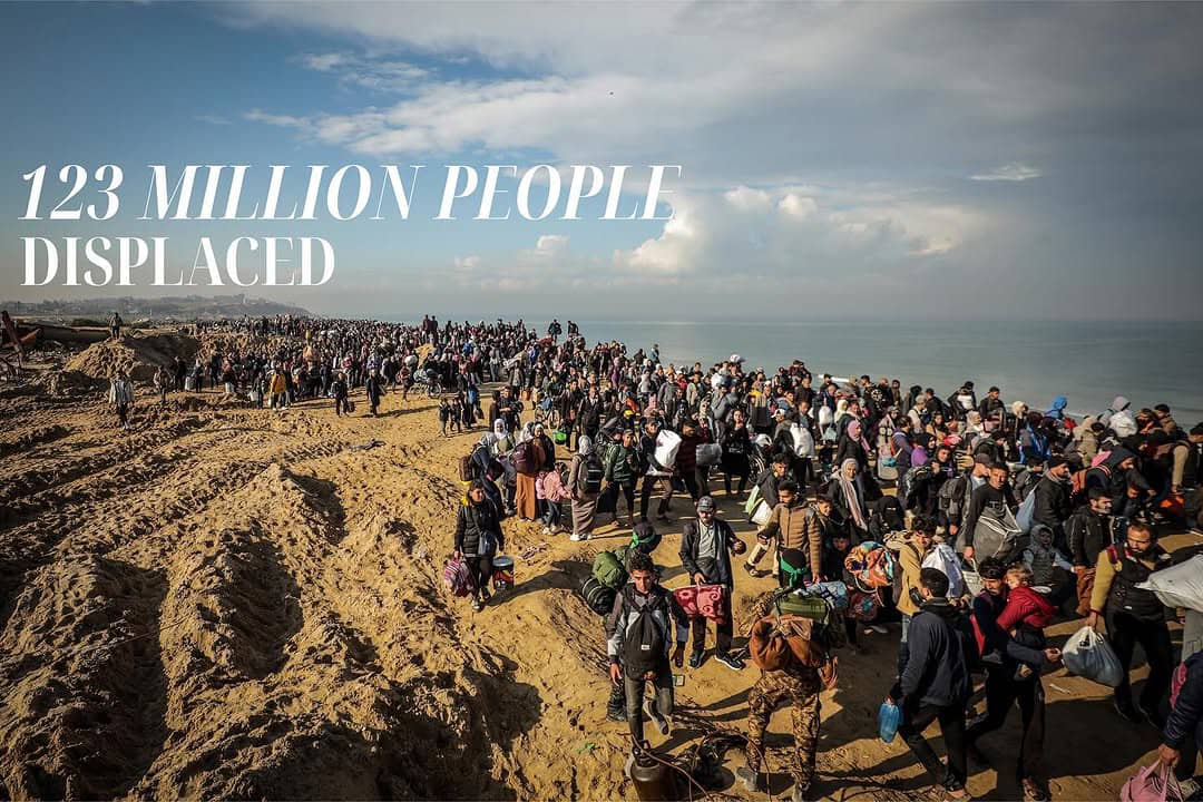 Displaced families moving together across a sandy landscape